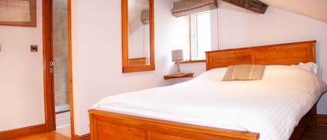 Un dormitorio con una cama de madera, un espejo grande y una ventana con vistas al exterior.