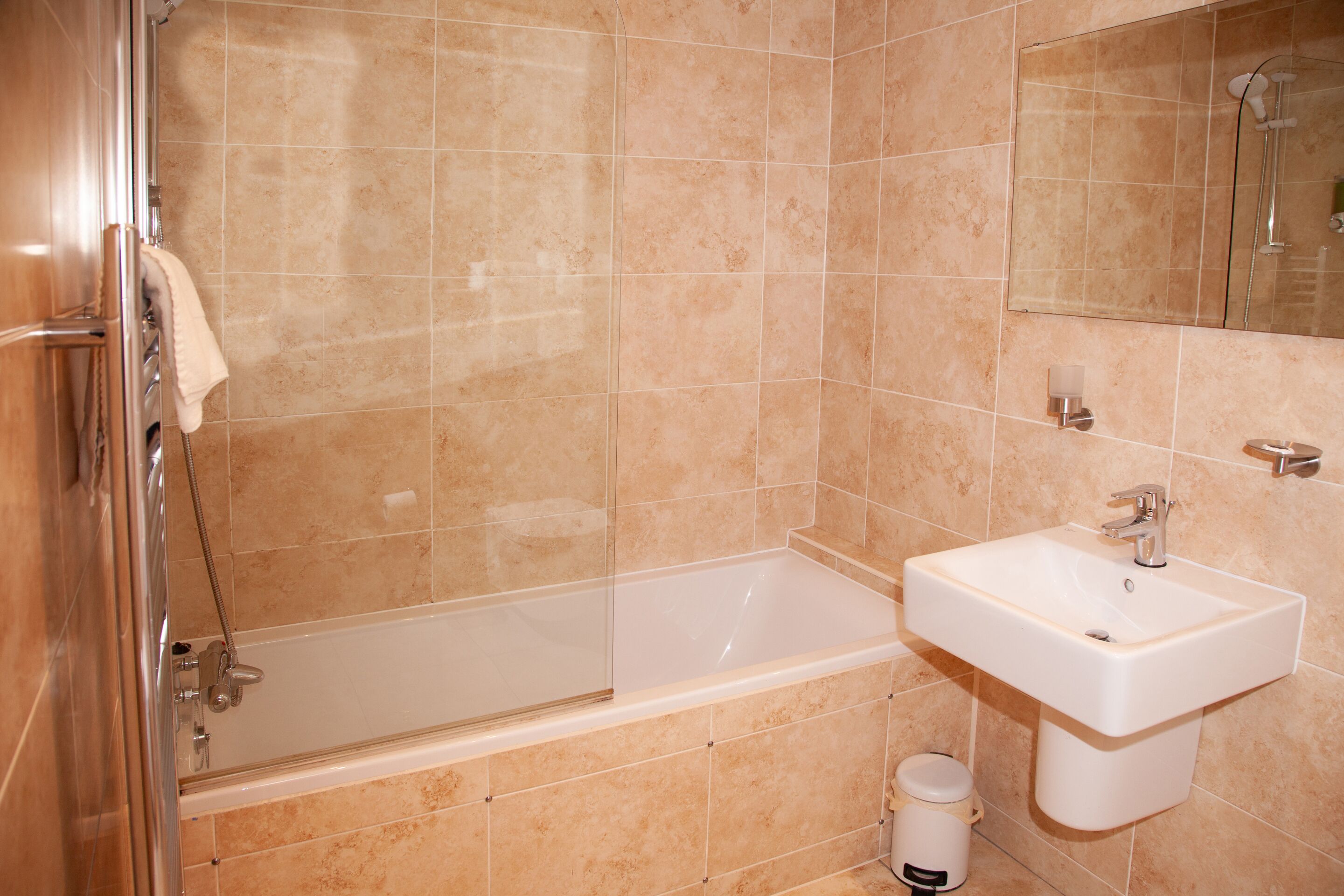 A bathroom with a bathtub, a sink, and a mirror.