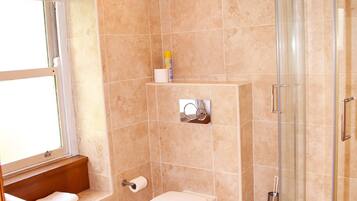 Baño con bañera, inodoro y cabina de ducha de vidrio.