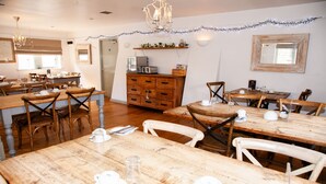 Un comedor con mesas y sillas de madera, un armario de madera y un candelabro.