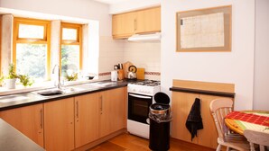 Cocina con armarios de madera, estufa, pileta y ventana.