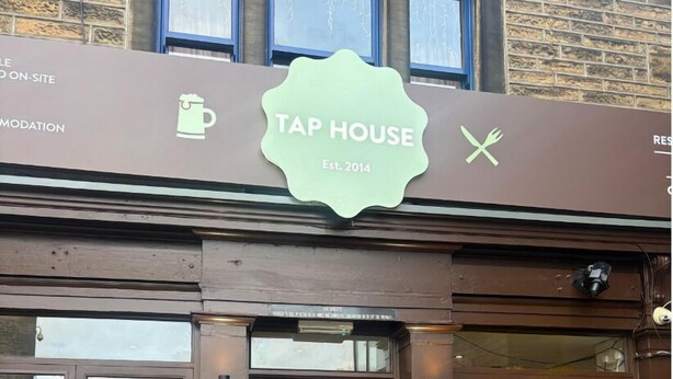 Un bar de cervezas artesanas con fachada marrón, puertas de vidrio y un letrero que indica su fundación en 2014.