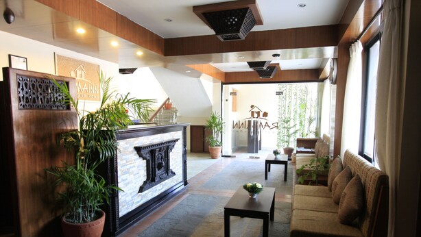 A lobby with a reception desk, a sofa, a coffee table, and potted plants. - Rama Inn Boutique Home (Kathmandu)