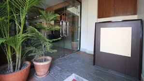 A reception area with a glass door, potted plants, a wooden cabinet, and a stone floor. - Rama Inn Boutique Home (Kathmandu)