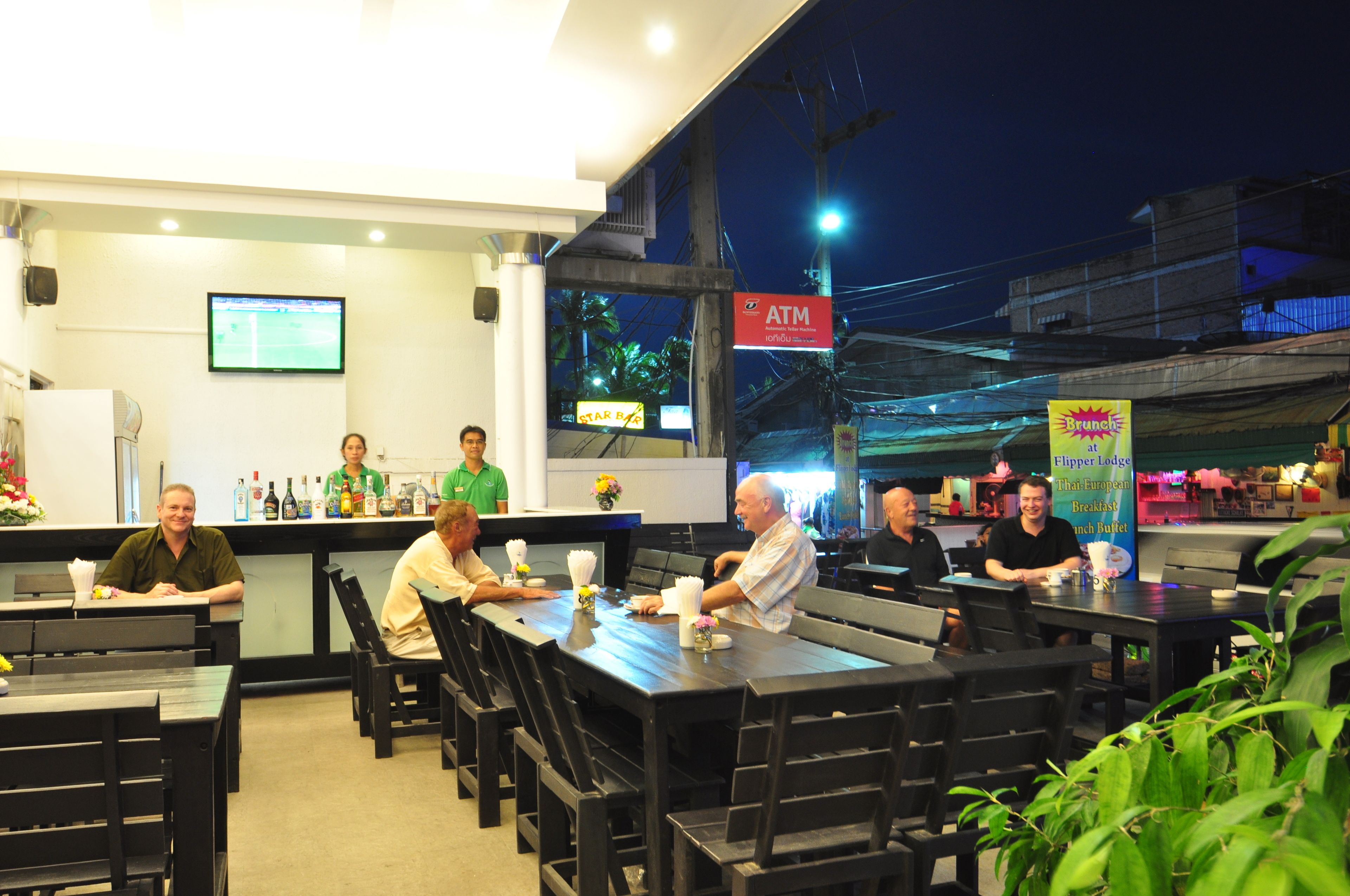 A restaurant with outdoor seating, a bar area, and a visible ATM sign.