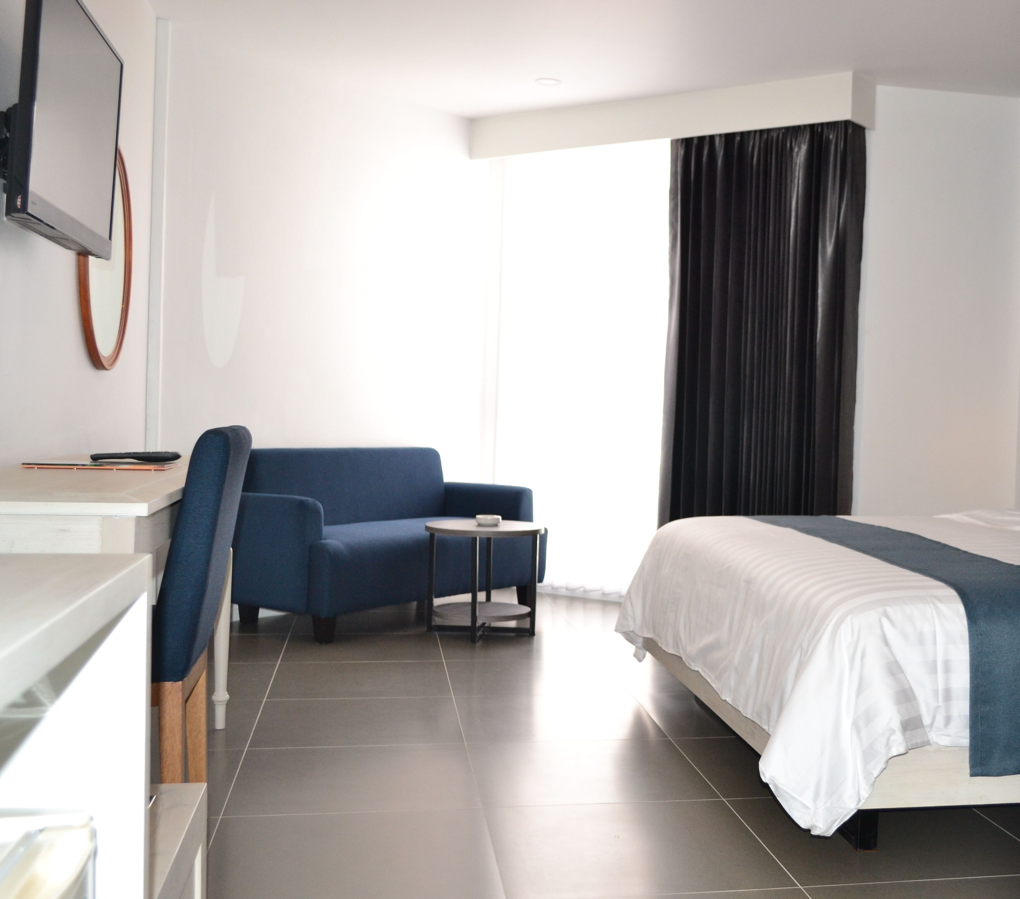 Een moderne hotelkamer met een bed, een bureau, een stoel, een klein tafeltje en een televisie.