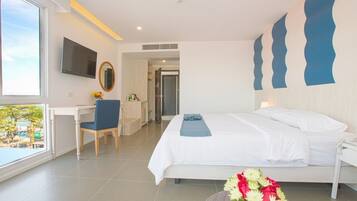 A modern hotel room with a bed, a desk, a chair, and a TV.