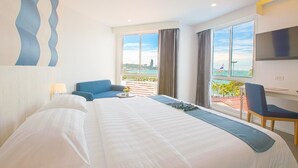 Quarto de hotel com uma cama grande, uma escrivaninha com cadeira, televisão na parede e varanda com vista para a cidade.