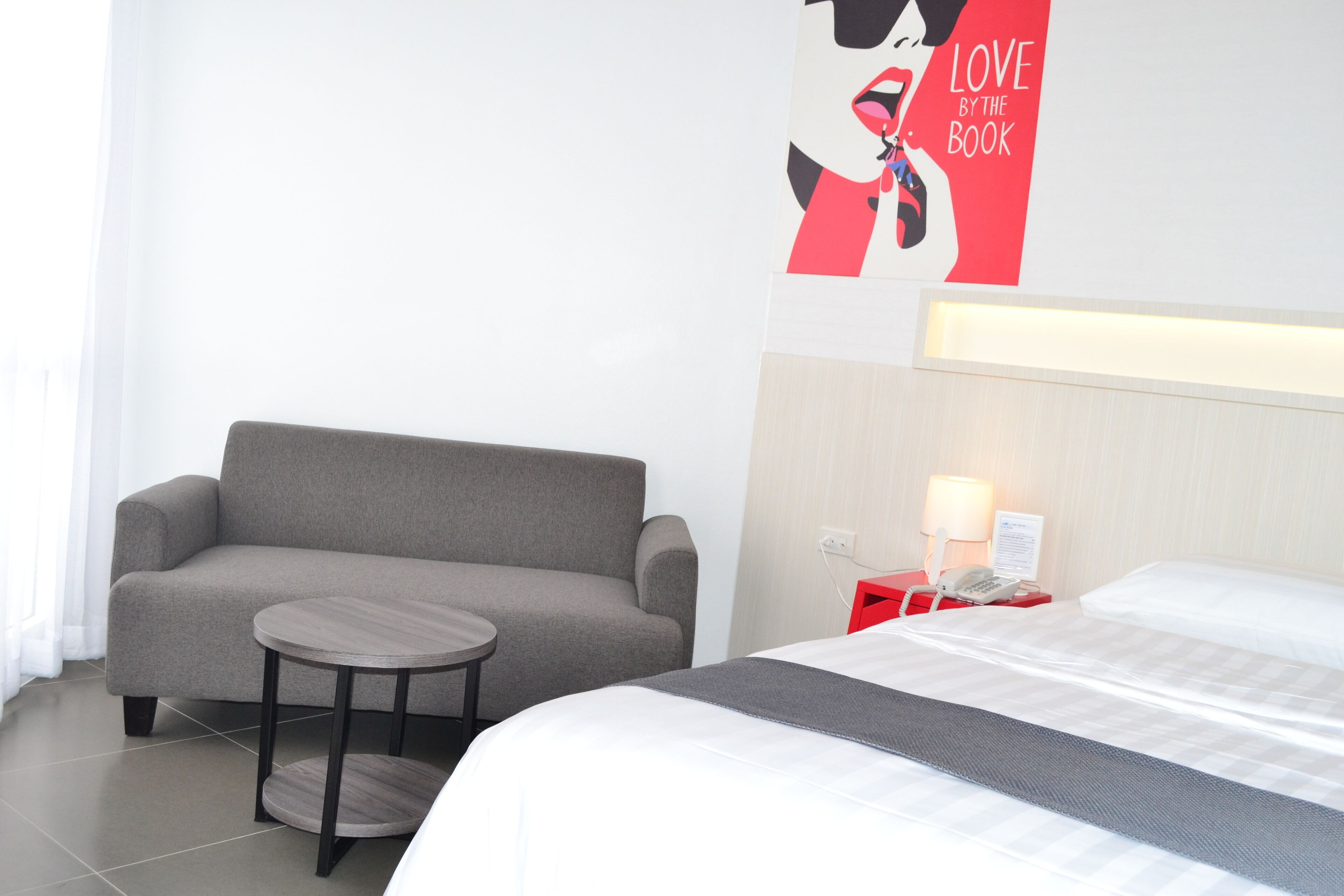 Ein Hotelzimmer mit einem Bett, einem Sofa, einem kleinen runden Tisch, einer Lampe und einer Wanddekoration.