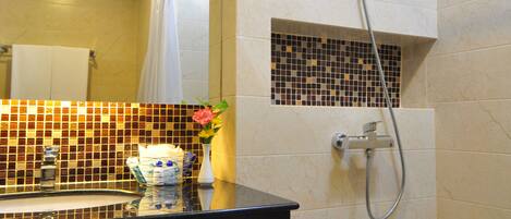 A bathroom with a black countertop, a shower with a handheld hose, and a tiled wall with a mosaic section.