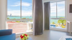 Quarto com grandes janelas, com vista para a praia e para a paisagem urbana.