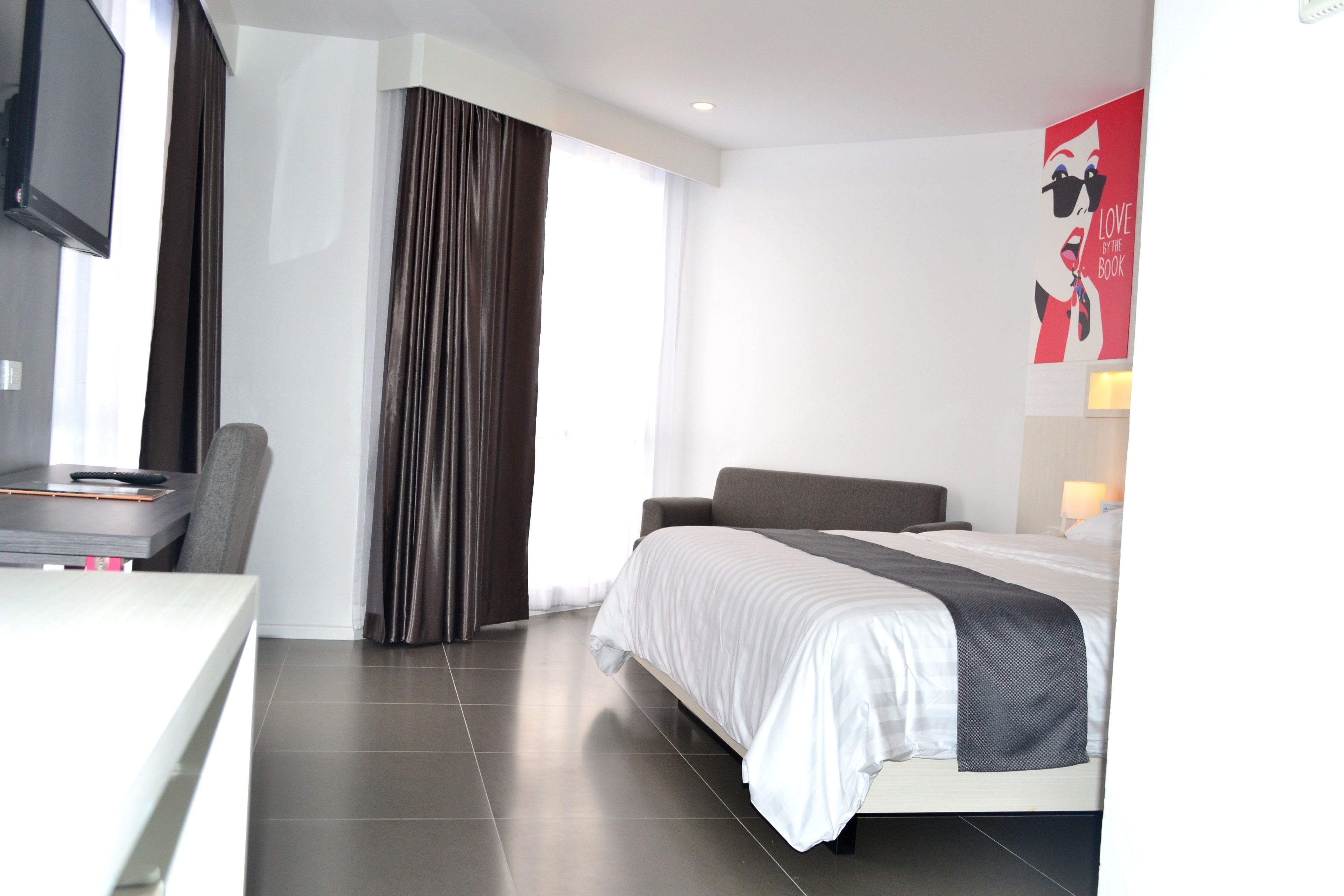 A modern hotel room with a bed, a desk, and a chair.