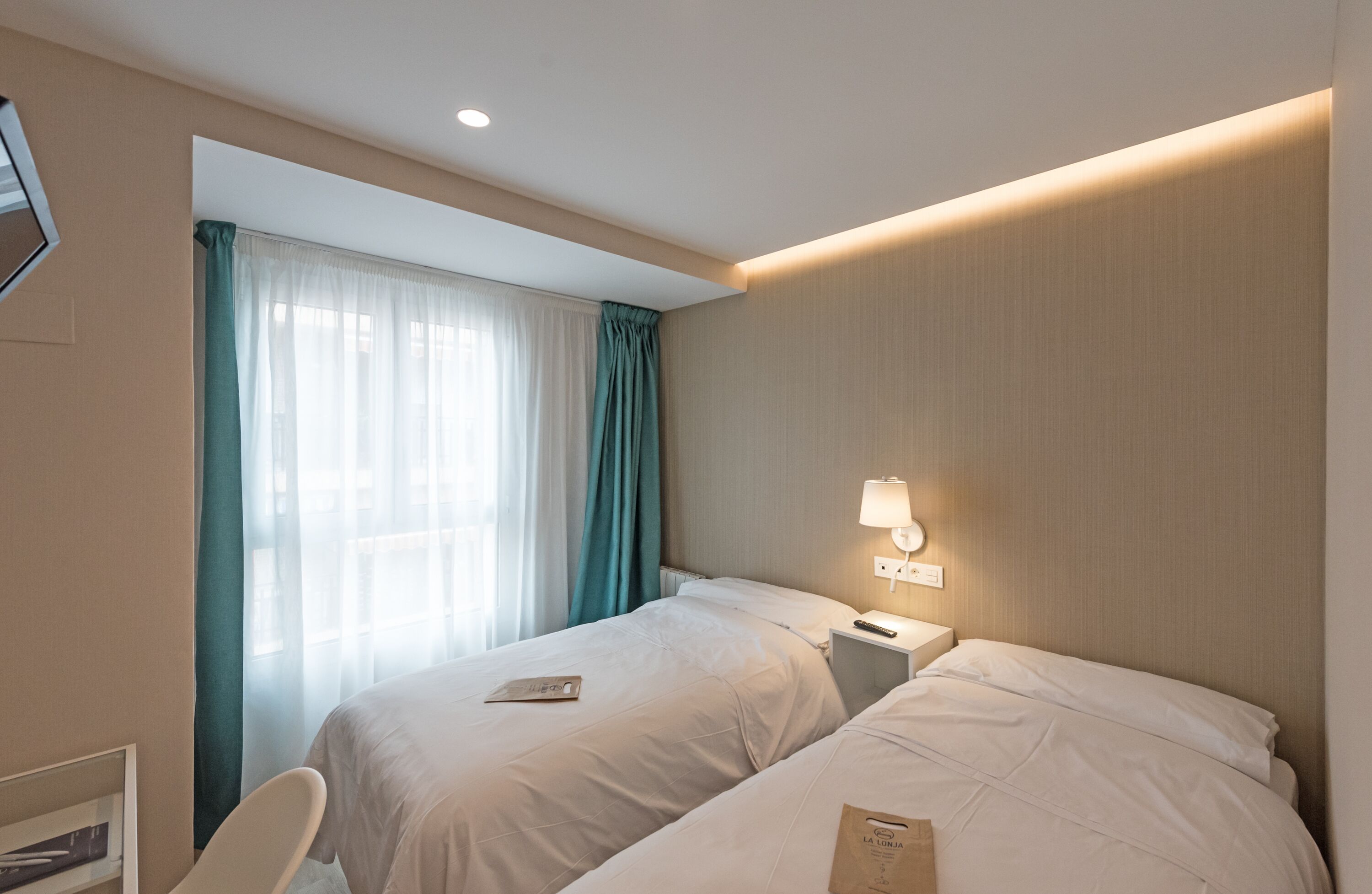 Une chambre d’hôtel avec deux lits, un bureau, une chaise et une fenêtre avec des rideaux.