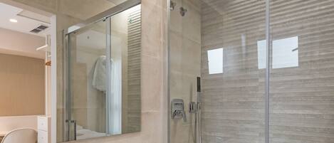 A modern bathroom with a glass-enclosed shower, a white sink, and a large mirror.