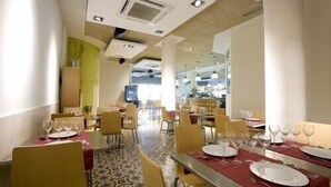 Ein Restaurant mit gedeckten Tischen, Stühlen und einem gemusterten Boden.