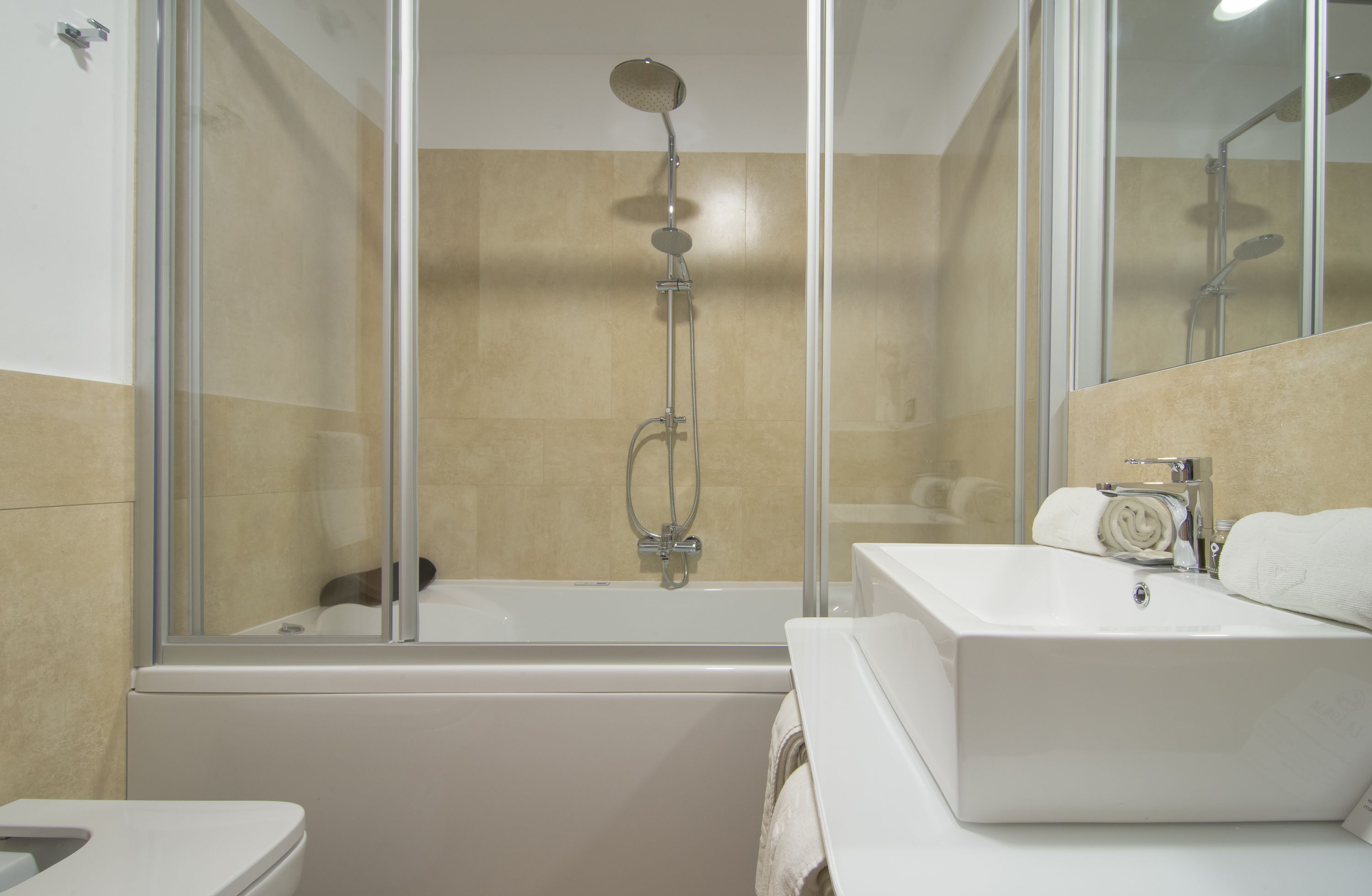 A modern bathroom with a glass-enclosed shower, a white bathtub, and a sink with a mirror.