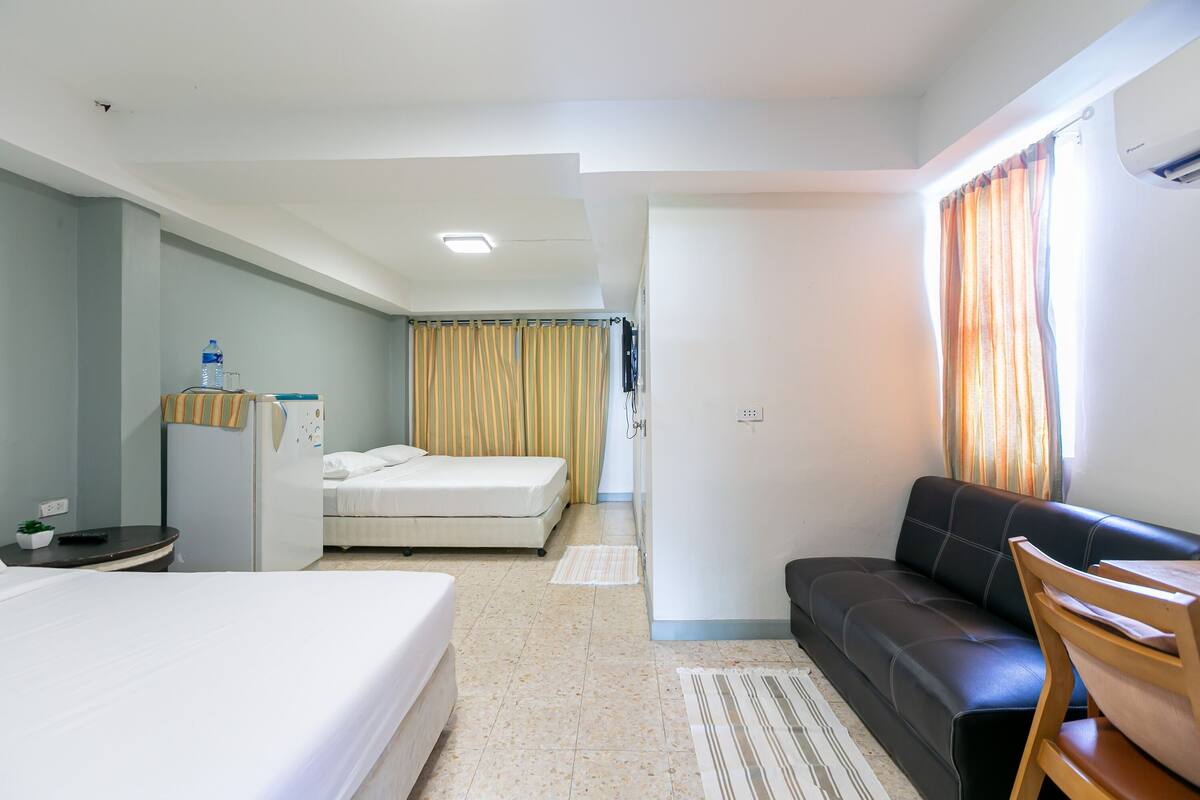 Ein Hotelzimmer mit einem Bett, einem Schlafsofa, einem kleinen Tisch und einem Kühlschrank.