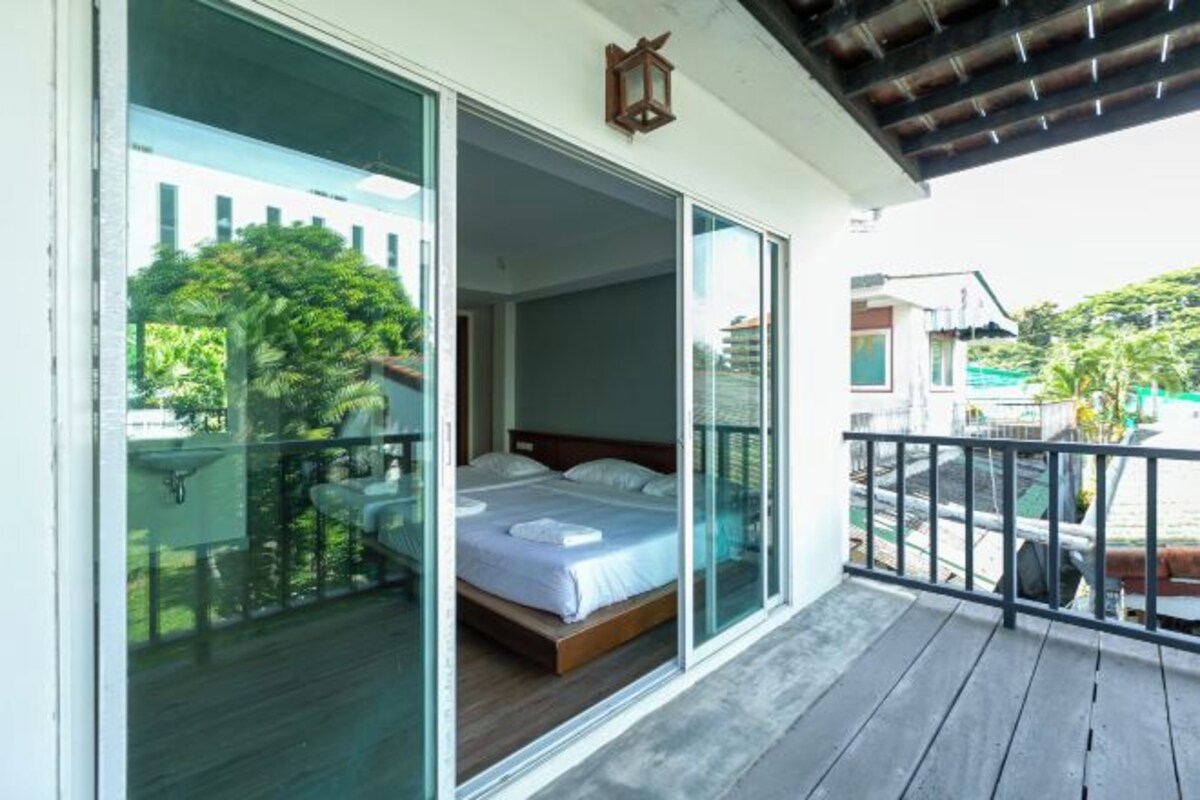 Una habitación con cama, balcón y vistas a zonas verdes y edificios.
