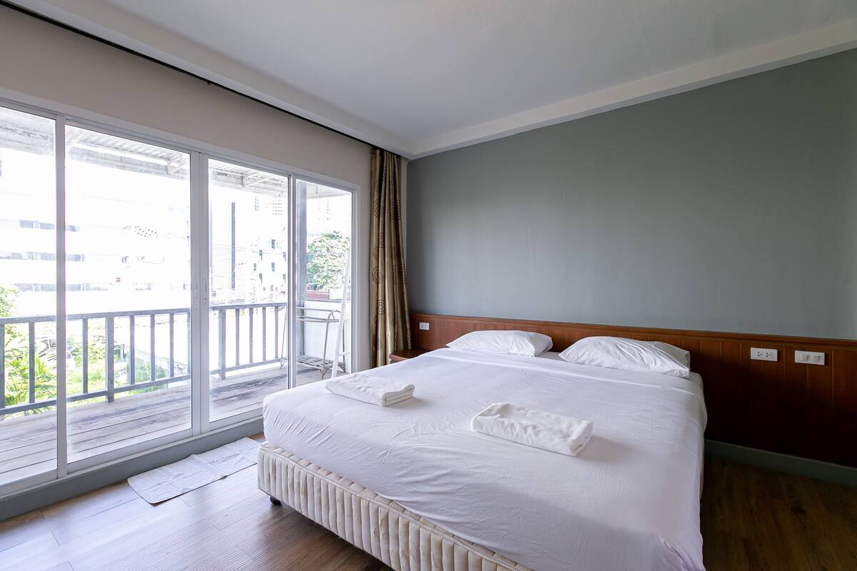 Ein Hotelzimmer mit großem Fenster, einem Bett mit weißer Bettwäsche und einem Holzkopfbrett.