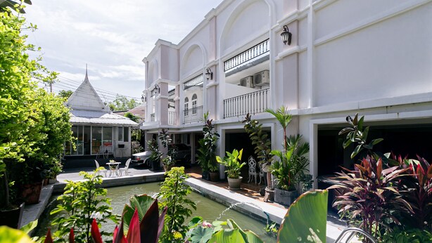 A courtyard with a pool, potted plants, and a white building with balconies. - Villa Lamai - Wong Amat House Pattaya (Pattaya)