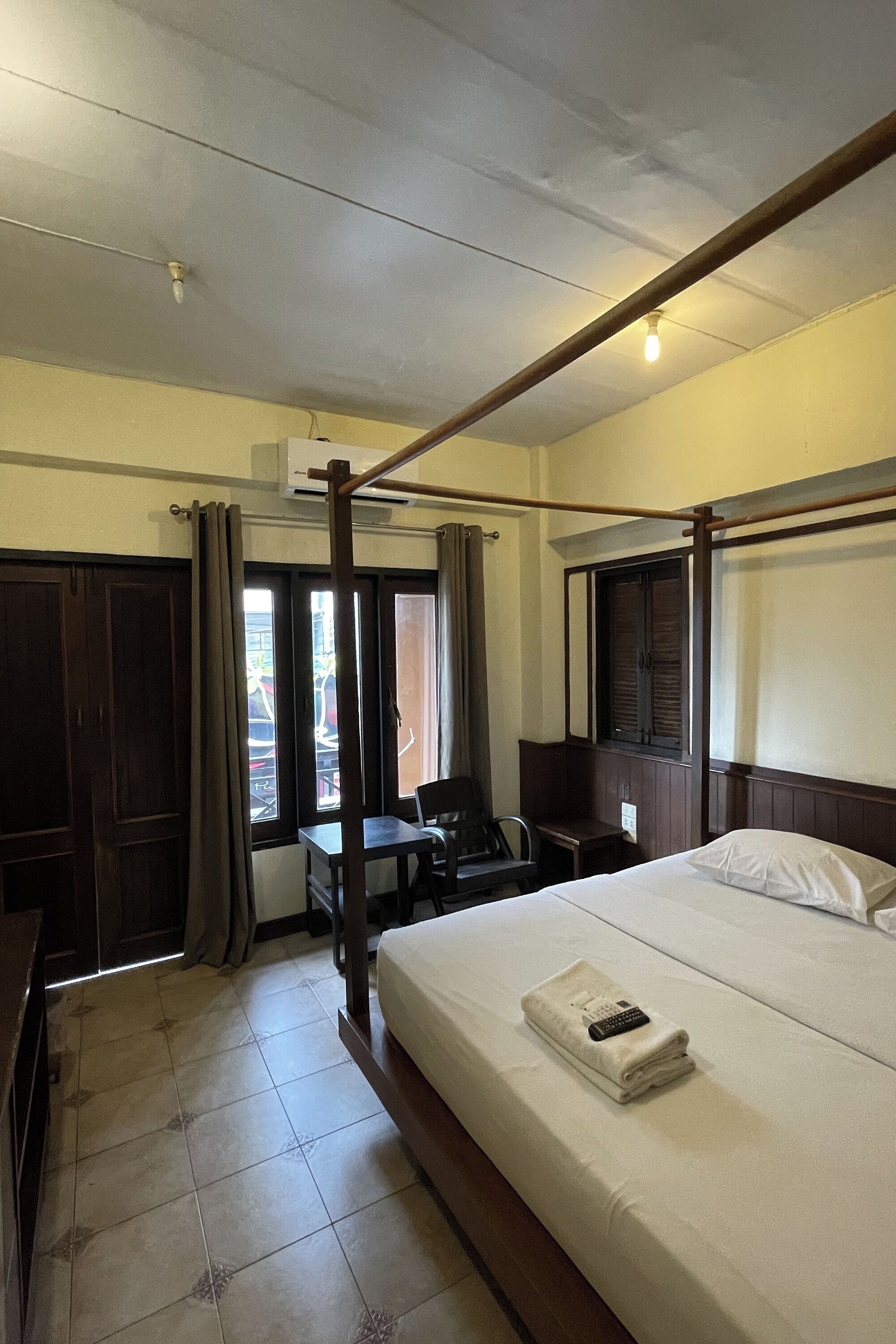 A hotel room with a bed, a desk, a chair, and a window.