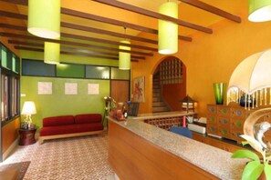 A lobby with a red sofa, a reception desk, and a staircase. - Keerati Homestay (Pattaya)