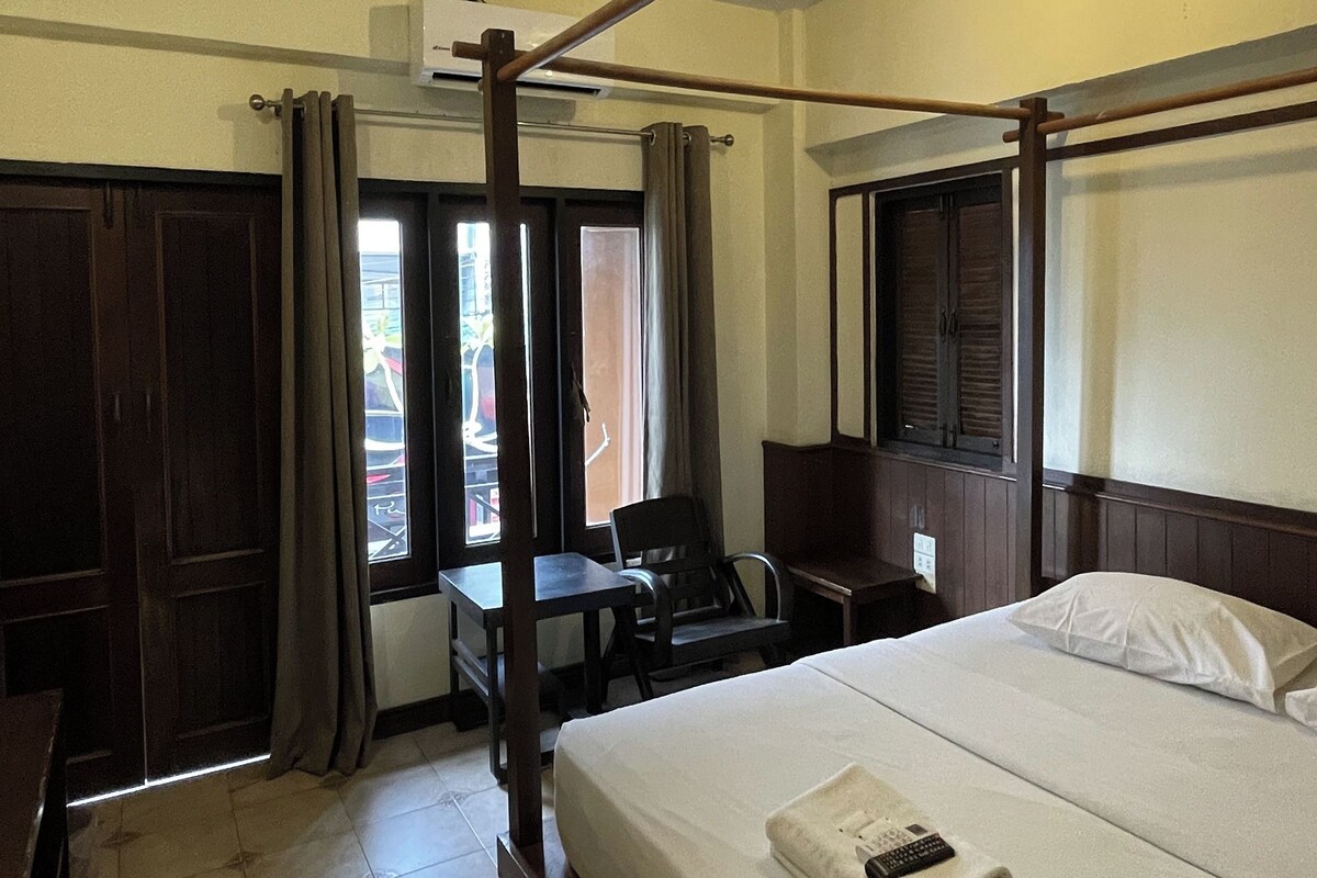 A hotel room with a bed, a desk, a chair, and a window.