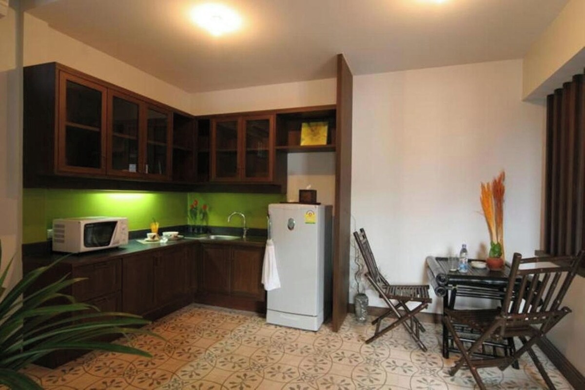 A compact kitchen with a microwave, refrigerator, and wooden cabinets.