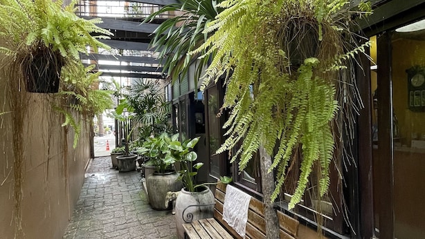 A narrow alleyway with a wooden bench, potted plants, and a hanging light fixture. - Keerati Homestay (Pattaya)