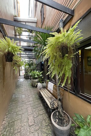 A narrow alleyway with a wooden bench, potted plants, and a hanging light fixture. - Keerati Homestay (Pattaya)