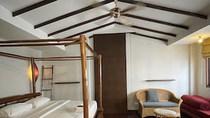 A spacious bedroom with a four-poster bed, a wooden ceiling, a ceiling fan, a wicker chair, a small table, and a red sofa. - Keerati Homestay (Pattaya)