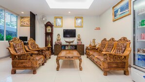 Un salon avec des meubles en bois richement décorés, un téléviseur et un réfrigérateur.