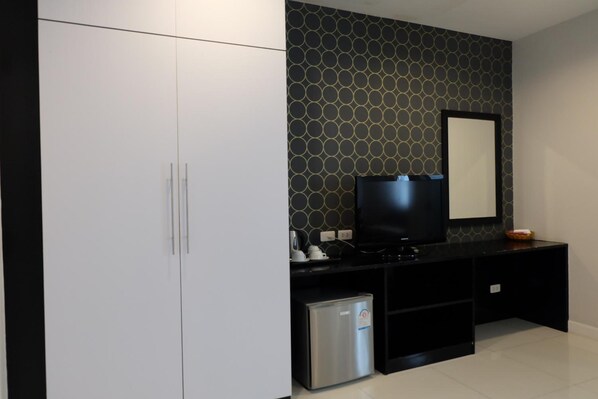 Un baño moderno con pared de azulejos blanco y negro, encimera negra, espejo y un refrigerador pequeño.