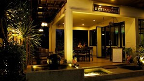 Un restaurant doté d’une terrasse, d’un élément décoratif aquatique et d’une enseigne indiquant qu’il s’agit d’un restaurant.