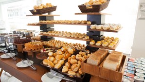 A buffet with various breads, pastries, and desserts displayed on wooden shelves. - Hotel Doral Guarujá (Guarujá)