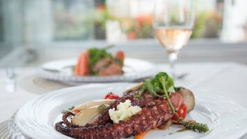 Prato de polvo com legumes e um copo de vinho sobre uma mesa.