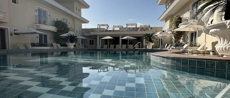 Una piscina al aire libre, sillones reclinables de piscina