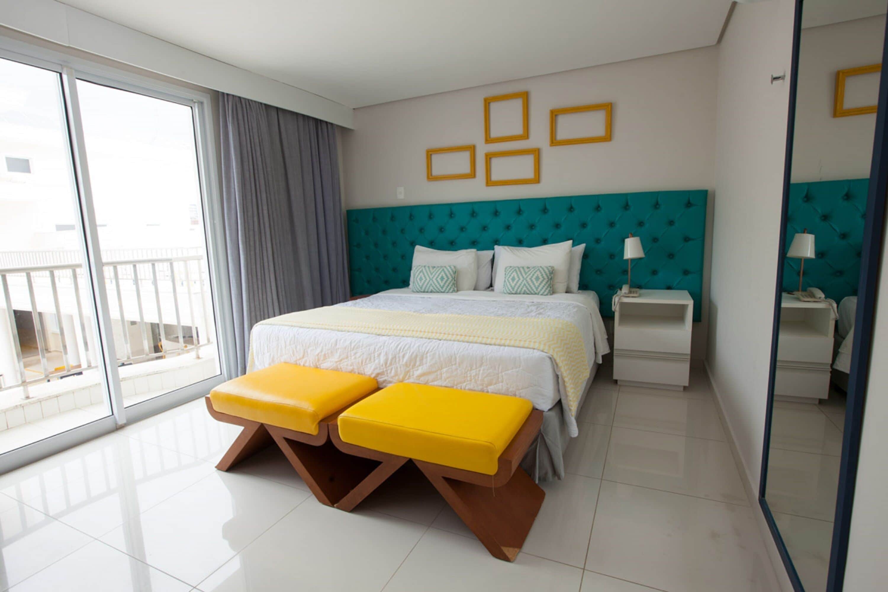 A modern hotel room with a large bed, a balcony, and a bright, clean design.