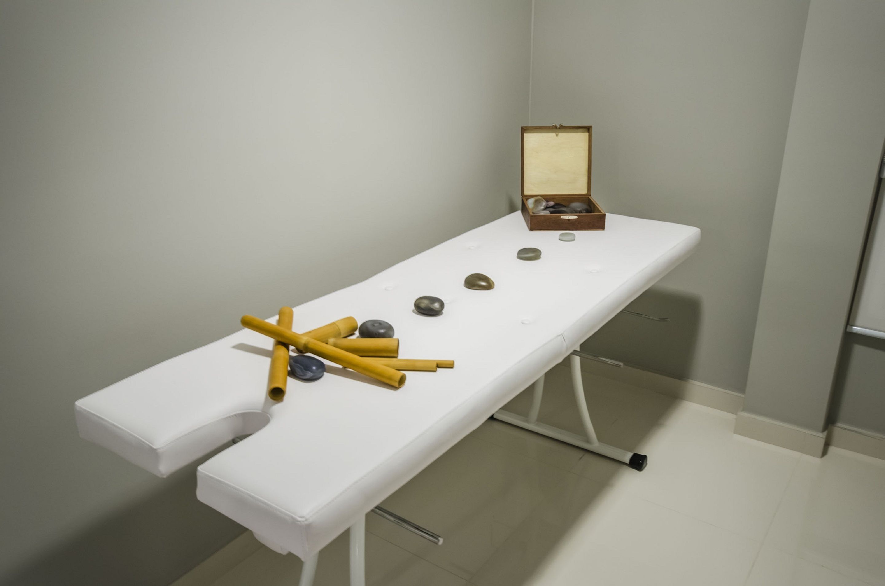 A white examination table with a wooden box and several stones.
