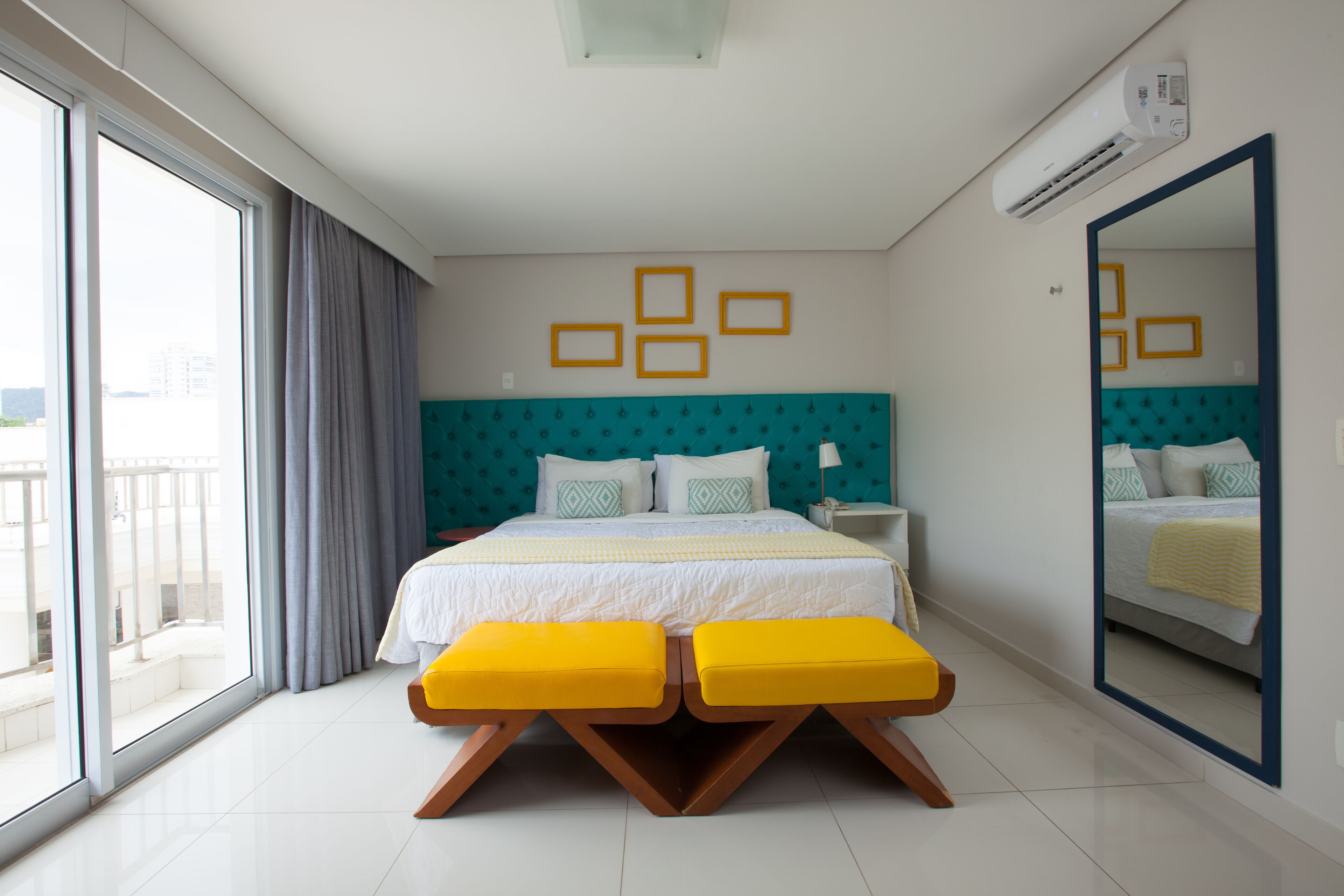 A modern hotel room with a large bed, a balcony, and a large mirror.