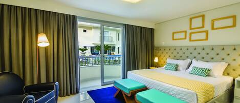 Habitación de hotel con una cama grande, un sofá, un banco y vistas al balcón exterior.