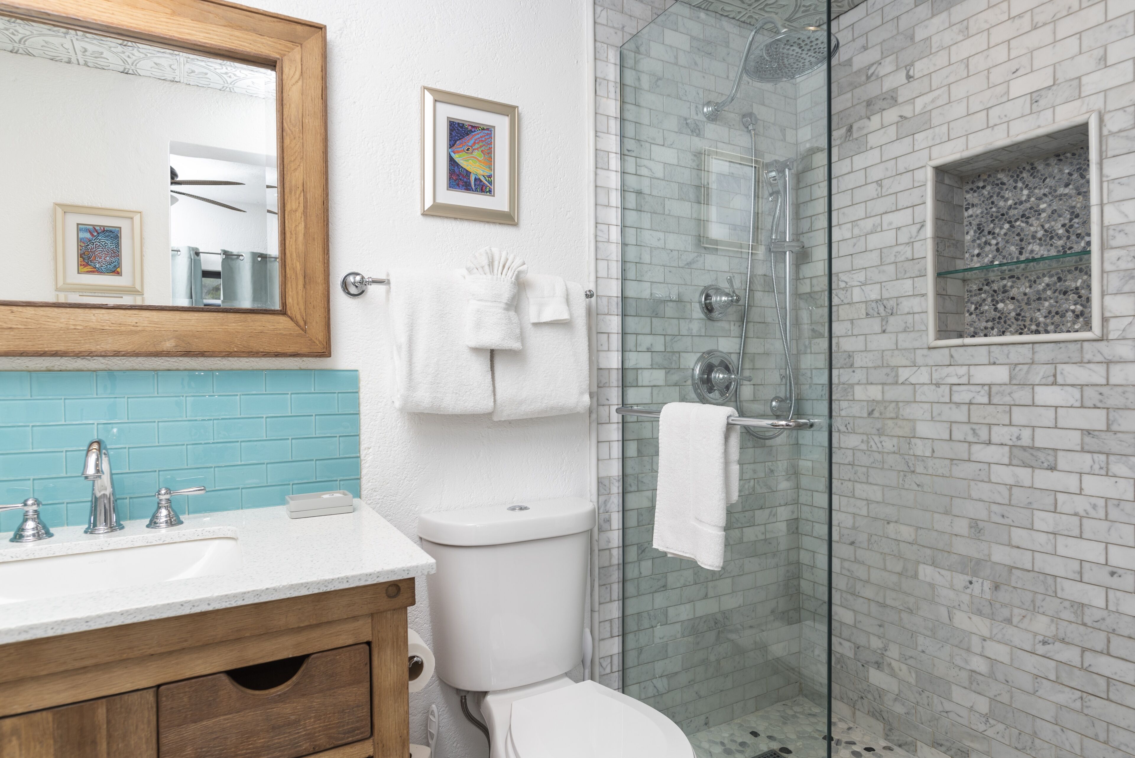 Ein Badezimmer mit Toilette, einer Duschkabine, einem Holzausleger mit Waschbecken und einem gerahmten Bild an der Wand.