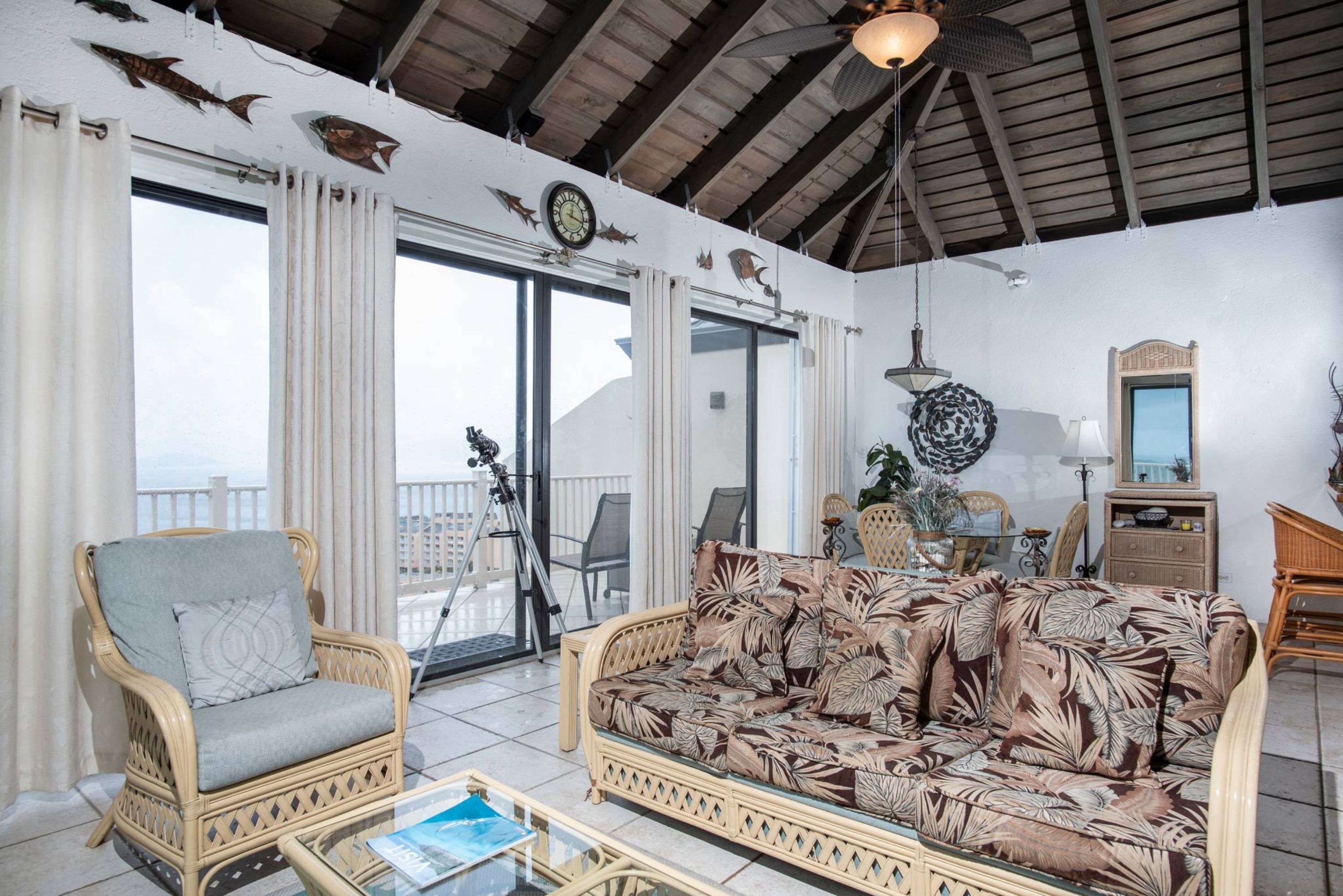 A living room with a wicker sofa, a wicker armchair, and a glass coffee table.