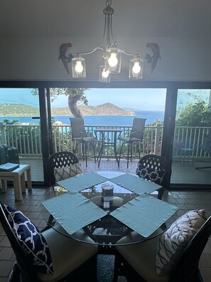 A dining area with a glass table, chairs, and a chandelier.