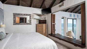 Ein Schlafzimmer mit Bett, Spiegel, Kommode und einem Fenster mit Blick.