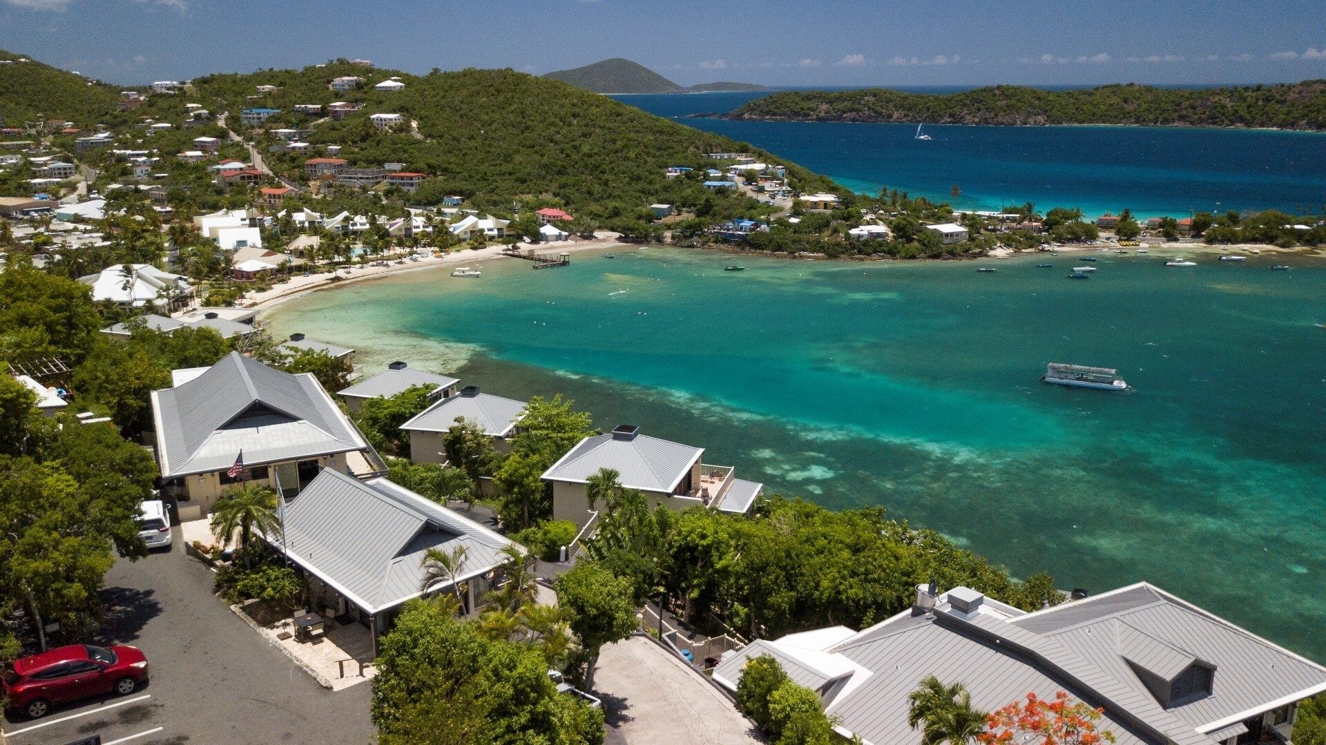 A coastal area with houses, a beach, and clear blue waters.