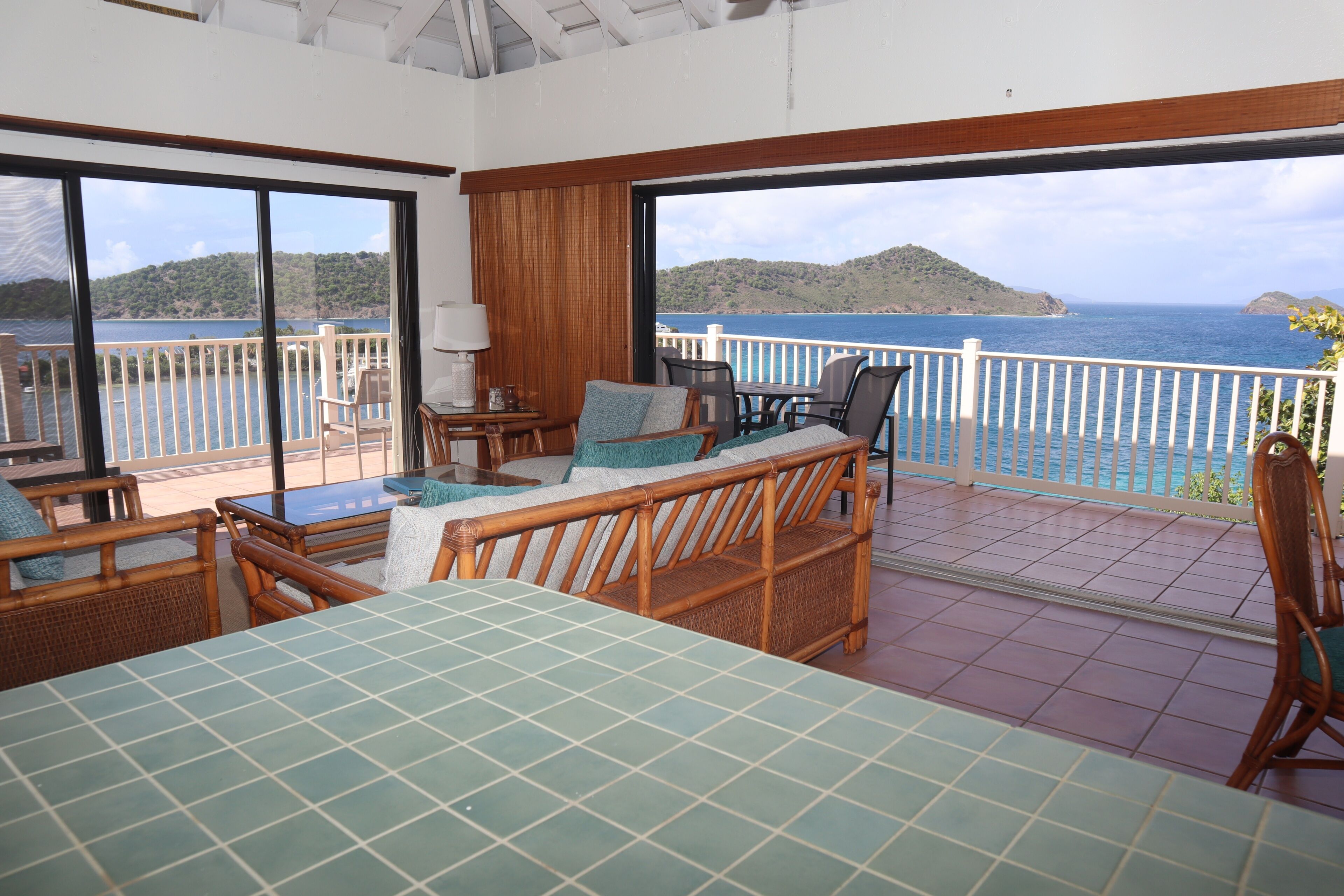 Un balcon avec vue sur la mer, des meubles en osier et une table.