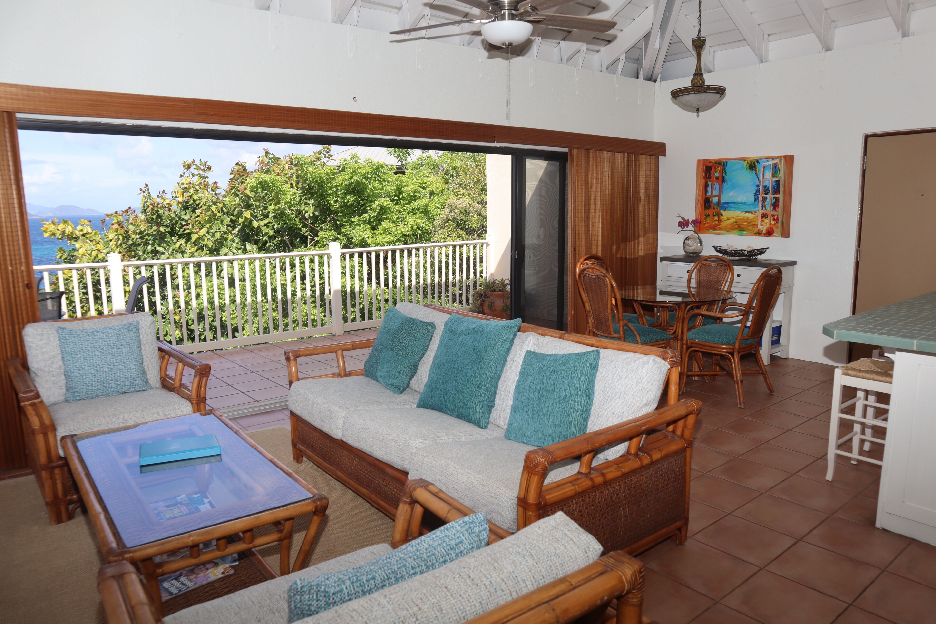 A balcony with wicker furniture, a dining area, and a view of the sea.