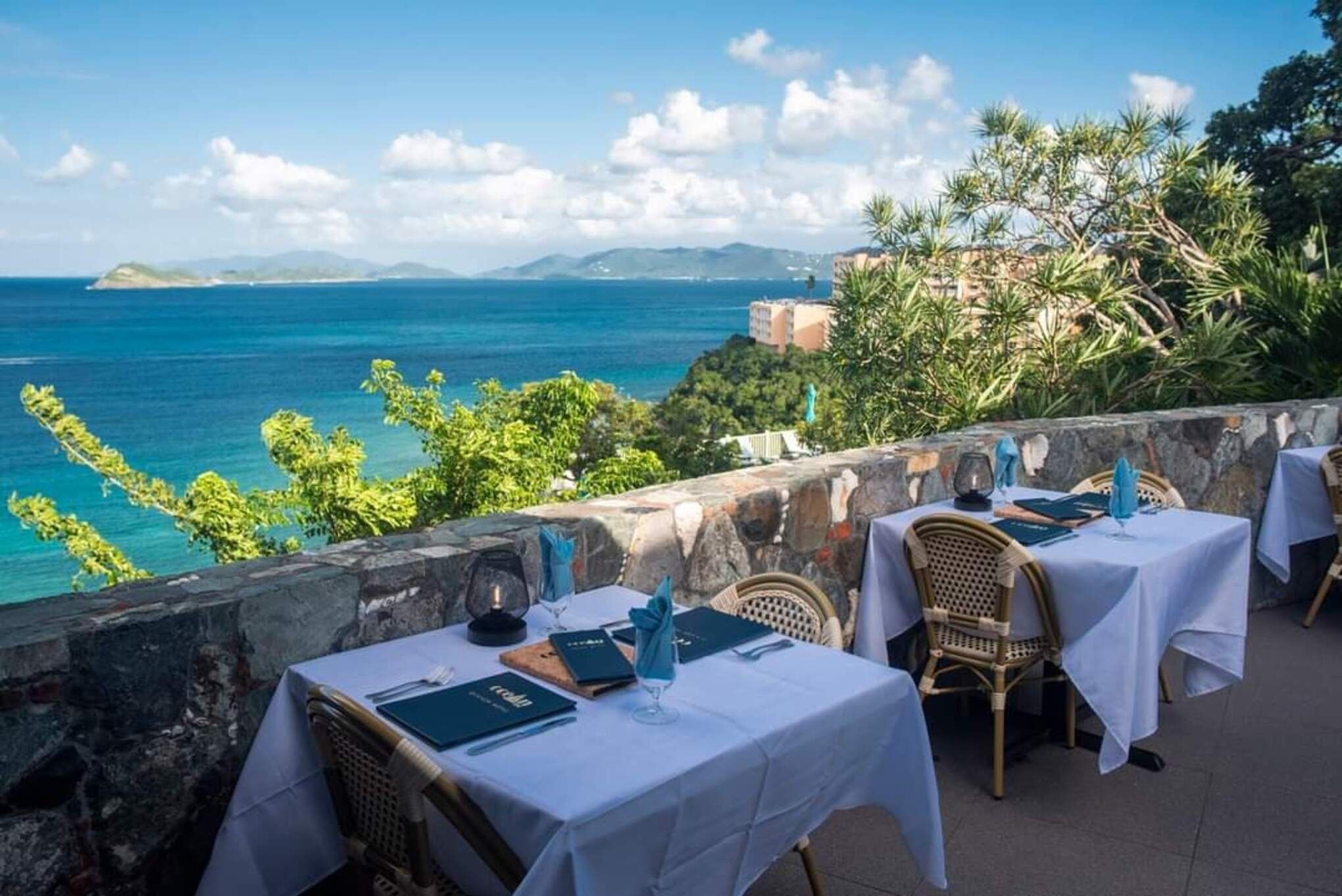 A seaside restaurant with tables set for dining, overlooking the ocean.