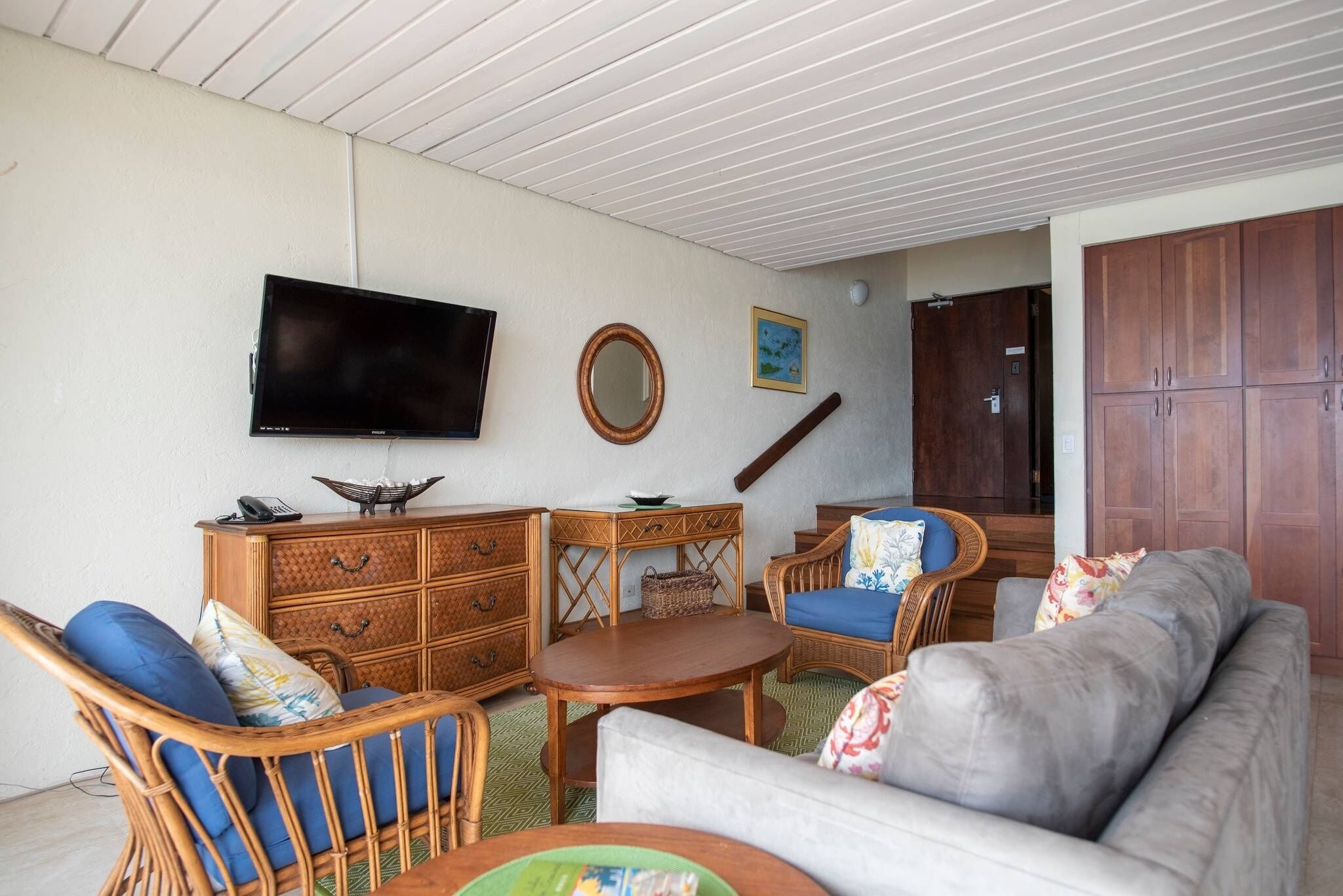 Una sala de estar con televisor, muebles de madera y un mueble grande.